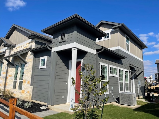 view of front of home featuring a front yard, central air condition unit, fence, and board and batten siding