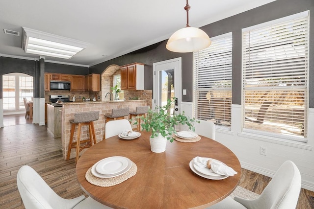 dining space featuring visible vents, arched walkways, and wood finished floors