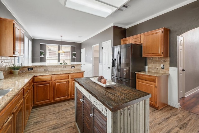 kitchen with visible vents, wood finished floors, arched walkways, and stainless steel refrigerator with ice dispenser