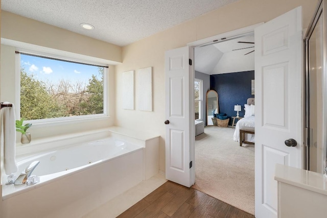 ensuite bathroom featuring a jetted tub, wood finished floors, ensuite bathroom, and a textured ceiling