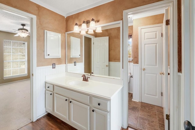 bathroom featuring a wainscoted wall, a textured ceiling, ceiling fan, and vanity