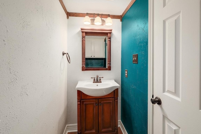 bathroom with vanity, crown molding, baseboards, and a textured wall