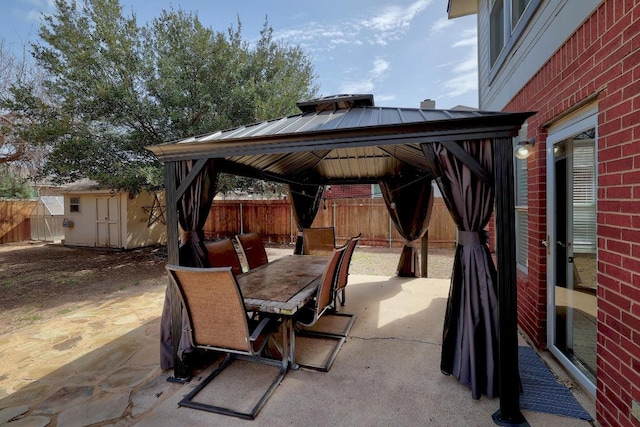 view of patio with outdoor dining space, a fenced backyard, an outdoor structure, a gazebo, and a storage unit