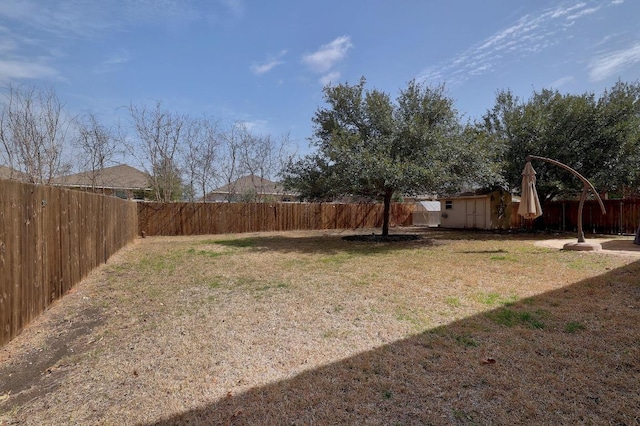 view of yard with a storage unit, an outdoor structure, and a fenced backyard