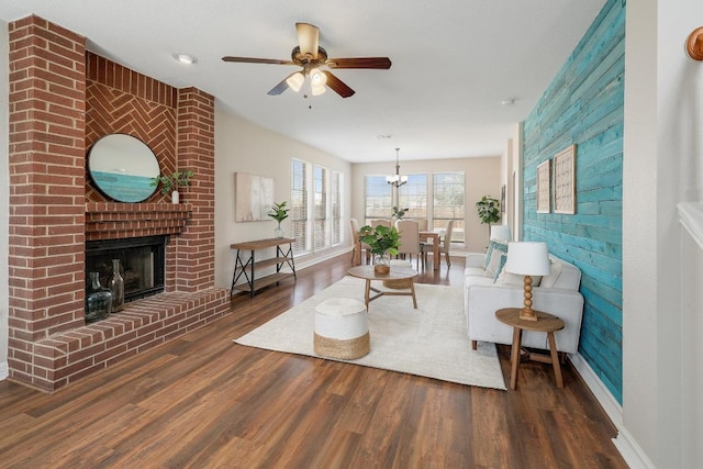 living area with ceiling fan, baseboards, wood finished floors, and a fireplace