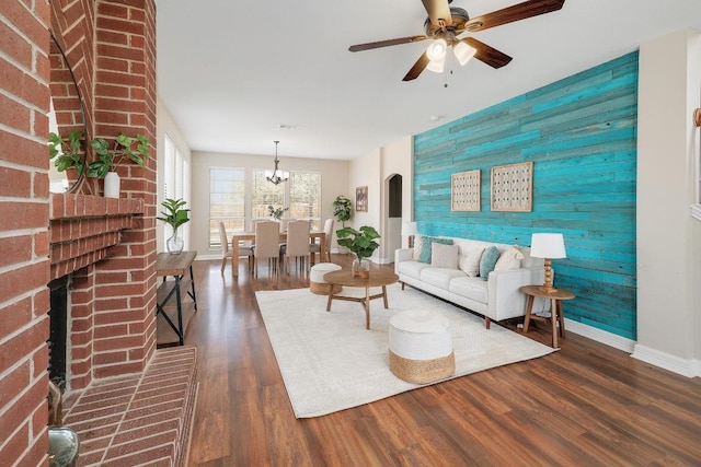 living area with wooden walls, wood finished floors, visible vents, baseboards, and an accent wall