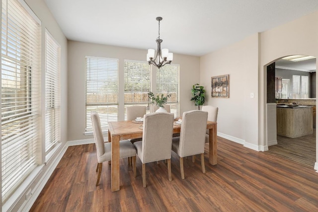 dining room featuring an inviting chandelier, dark wood-style floors, arched walkways, and baseboards