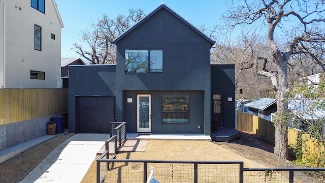 view of front of property featuring stucco siding, an attached garage, a fenced front yard, and driveway