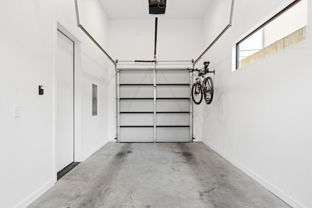 garage featuring a garage door opener, electric panel, and baseboards