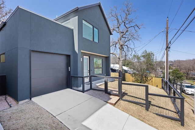 contemporary house with stucco siding, driveway, an attached garage, and fence