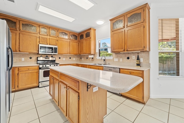 kitchen with a sink, a kitchen island, appliances with stainless steel finishes, light countertops, and light tile patterned floors