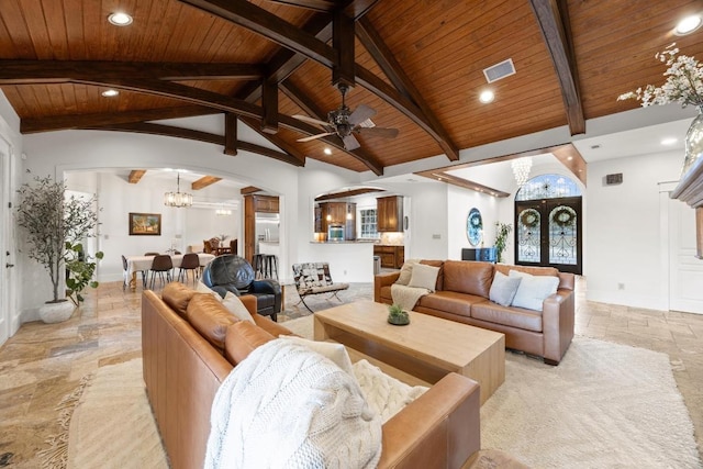 living area featuring beamed ceiling, arched walkways, stone tile floors, and wooden ceiling