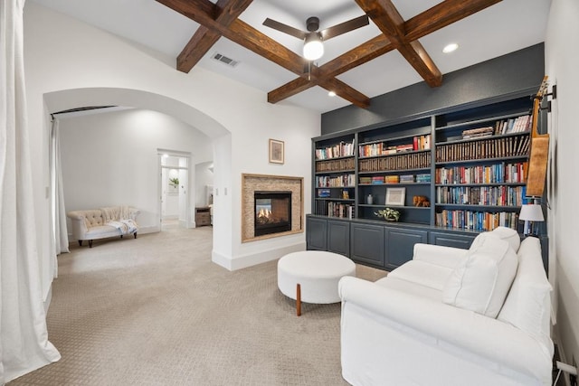 living area featuring visible vents, light carpet, beam ceiling, arched walkways, and coffered ceiling