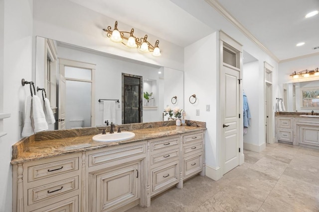 bathroom with a sink, two vanities, ornamental molding, and recessed lighting