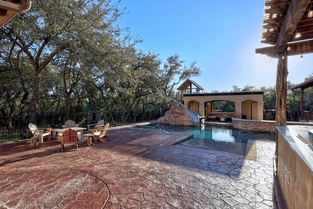 view of pool featuring fence, a fenced in pool, a water slide, a fireplace, and a patio area