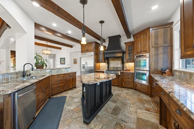 kitchen with brown cabinets, custom range hood, a sink, stone tile flooring, and stainless steel appliances