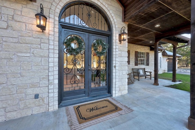 doorway to property with covered porch and stone siding