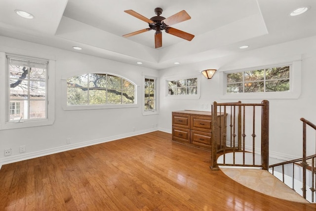 unfurnished bedroom with a raised ceiling, recessed lighting, baseboards, and light wood finished floors