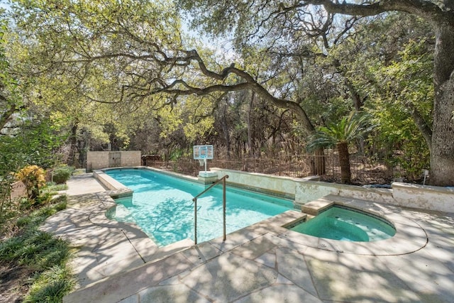 pool with an in ground hot tub and a patio area