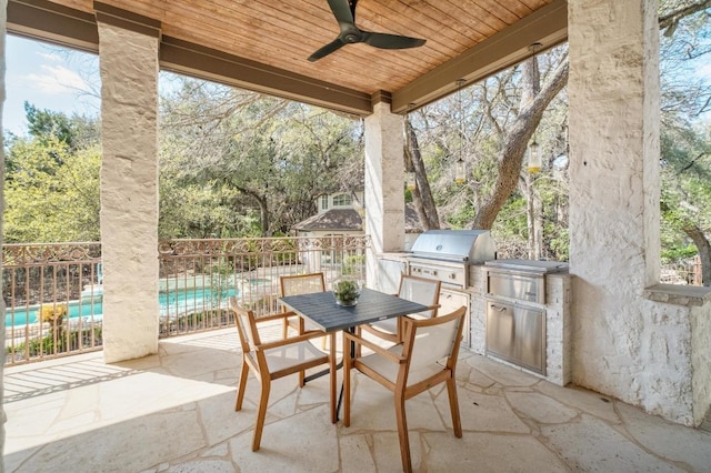 view of patio / terrace featuring ceiling fan, area for grilling, fence, and an outdoor kitchen