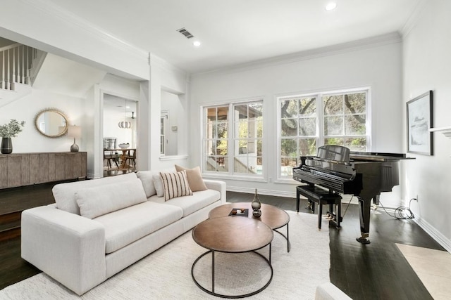 living room with baseboards, wood finished floors, visible vents, and ornamental molding