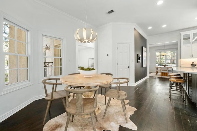 dining area with dark wood-style floors, visible vents, crown molding, and baseboards