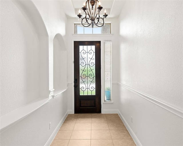 entrance foyer featuring light tile patterned floors, baseboards, a wealth of natural light, and a chandelier