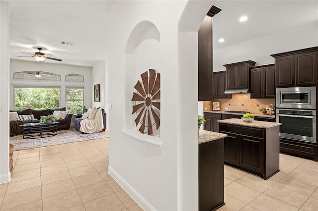 kitchen with tasteful backsplash, dark brown cabinets, open floor plan, light tile patterned floors, and appliances with stainless steel finishes