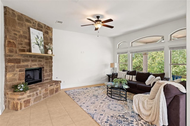 living room featuring a ceiling fan, baseboards, visible vents, a fireplace, and tile patterned flooring