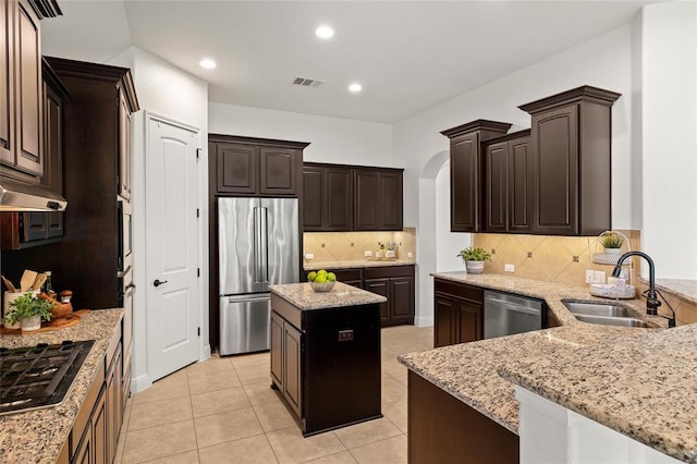 kitchen featuring visible vents, a sink, light stone counters, appliances with stainless steel finishes, and dark brown cabinets