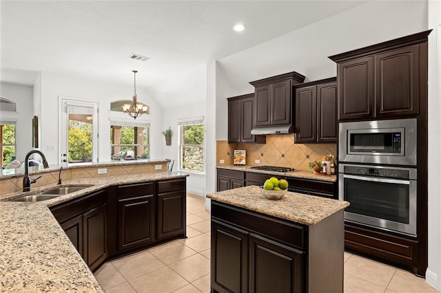 kitchen featuring a sink, under cabinet range hood, backsplash, stainless steel appliances, and lofted ceiling