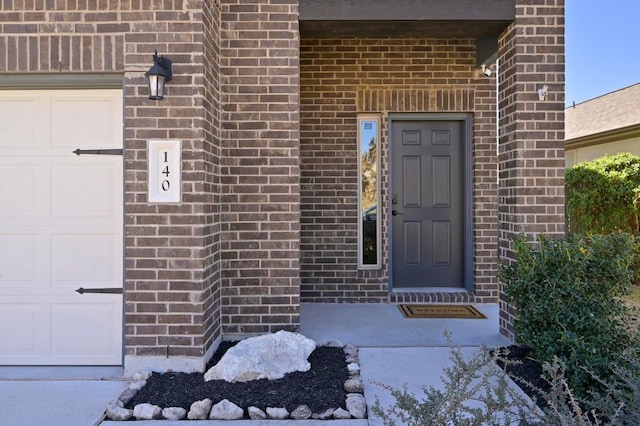 property entrance with brick siding and an attached garage