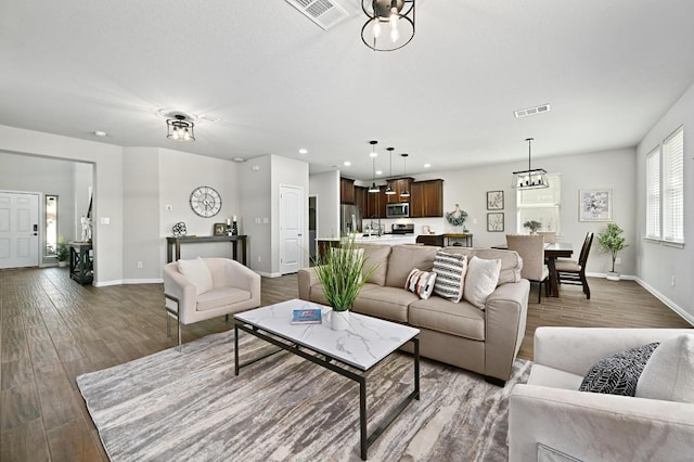 living area with recessed lighting, visible vents, baseboards, and wood finished floors