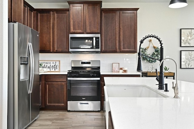 kitchen featuring a sink, light countertops, tasteful backsplash, and stainless steel appliances