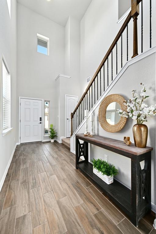 foyer with wood finish floors, visible vents, plenty of natural light, baseboards, and stairs