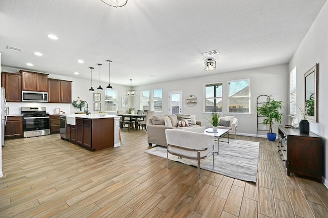 living room featuring visible vents, recessed lighting, light wood-type flooring, and baseboards