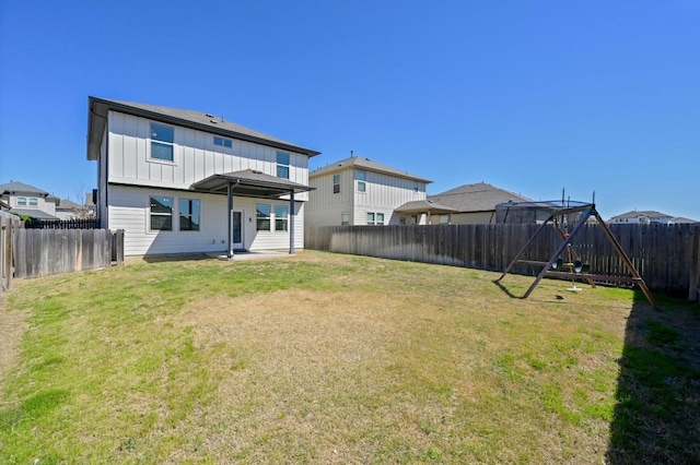 rear view of house featuring a yard, board and batten siding, a fenced backyard, and a playground