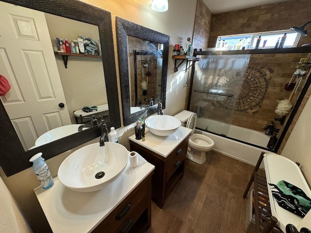 full bath featuring bath / shower combo with glass door, toilet, vanity, and wood finished floors