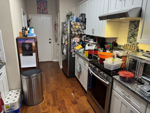 kitchen featuring dark stone countertops, stainless steel range with gas cooktop, dark wood-type flooring, under cabinet range hood, and tasteful backsplash