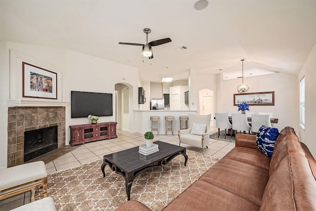 living room with arched walkways, light tile patterned floors, a fireplace, and visible vents