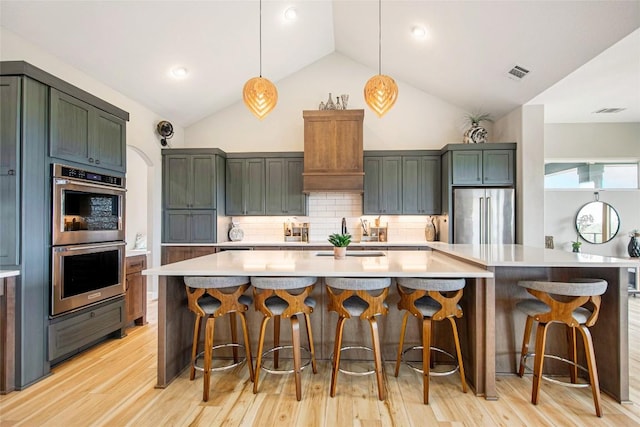 kitchen with visible vents, light wood-style flooring, tasteful backsplash, stainless steel appliances, and light countertops