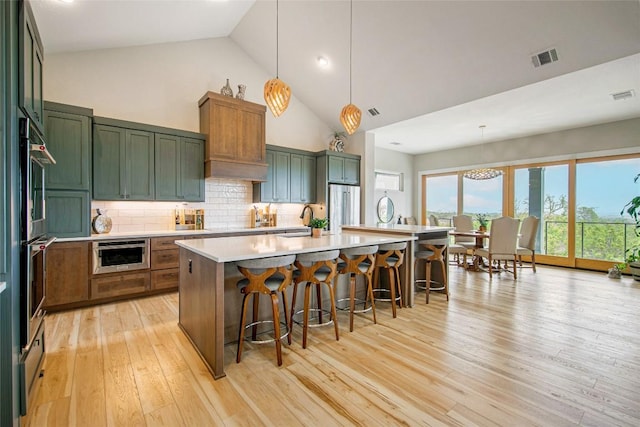 kitchen featuring visible vents, green cabinetry, light countertops, high end refrigerator, and backsplash