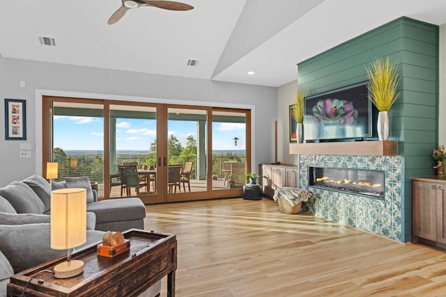 living room with visible vents, wood finished floors, french doors, a multi sided fireplace, and vaulted ceiling