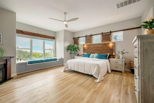 bedroom featuring ceiling fan, visible vents, baseboards, and light wood-style flooring