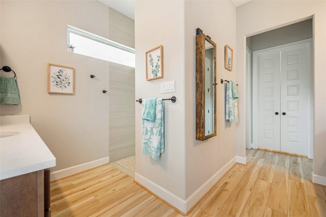 full bath with baseboards, wood finished floors, vanity, and a walk in shower