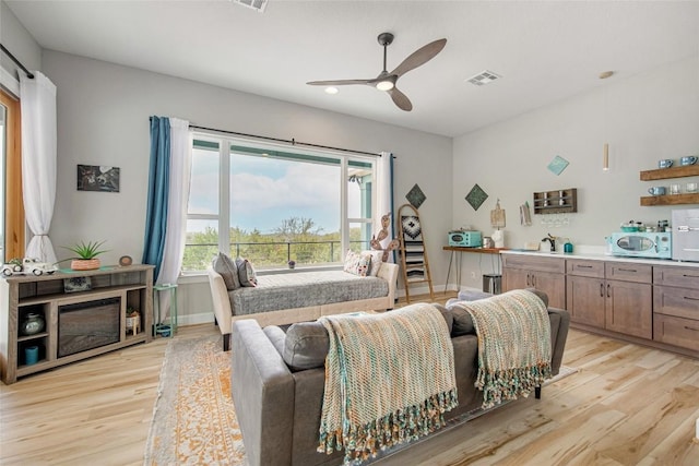 living area with ceiling fan, baseboards, visible vents, and light wood-type flooring