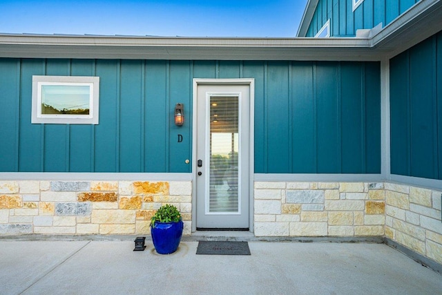 property entrance featuring board and batten siding and stone siding