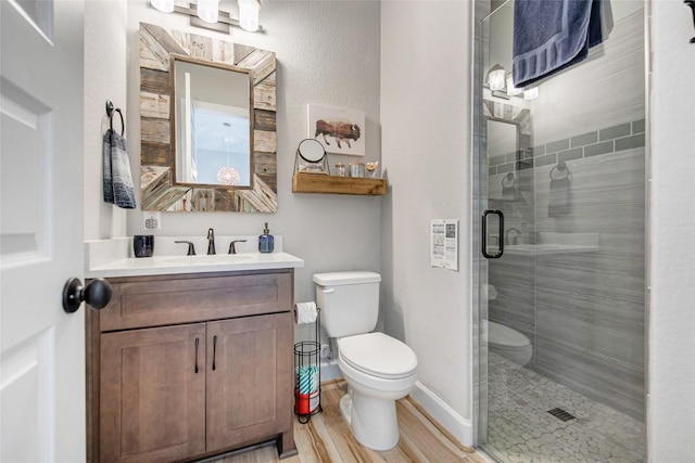 full bathroom featuring toilet, wood finished floors, a shower stall, baseboards, and vanity