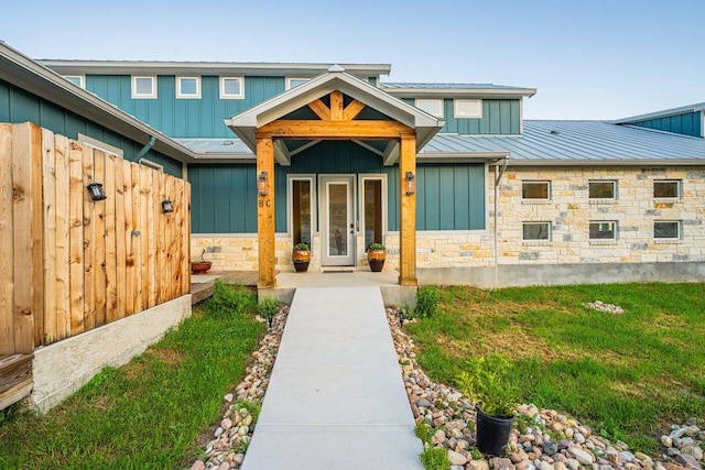 entrance to property featuring a standing seam roof, board and batten siding, stone siding, and metal roof