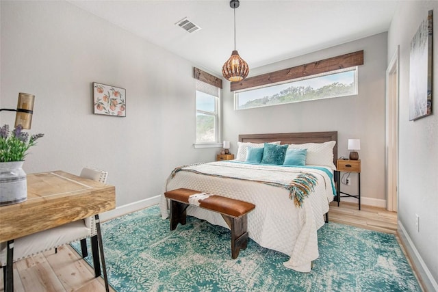 bedroom with visible vents, baseboards, and wood finished floors